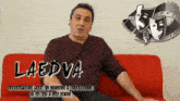 a man sits on a red couch with the word laedva on the bottom