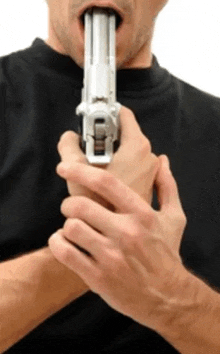 a man in a black shirt is holding a silver gun in his mouth