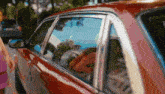 a woman is standing next to a red car