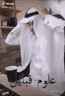 a man wearing a white shirt and a black head scarf with arabic writing on it