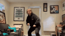 a man is dancing in a living room with a framed picture of a celtic jersey