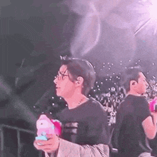 a man is standing on a stage holding a stuffed animal in his hands .