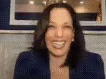 a woman with dark hair is smiling and wearing a blue jacket .