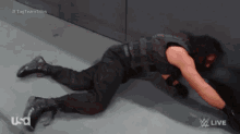 a wrestler is laying on the floor in front of a wall with usa live written on the bottom of the screen