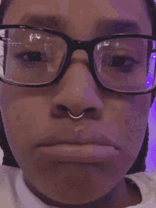 a woman wearing glasses and a nose ring makes a funny face