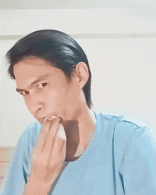 a man in a light blue shirt is biting his finger