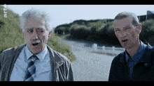 two men are standing next to each other on a road with a sign that says rtl