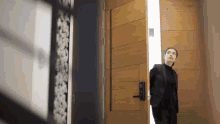 a woman in a black suit is standing in front of a door