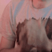 a man in a t-shirt is clapping his hands together in front of a pink wall .