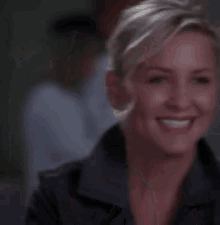 a close up of a woman smiling with her hand on her face .