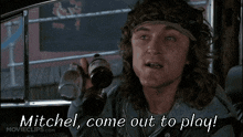 a man in a car is holding two bottles of beer and says mitchel come out to play