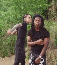 a man with dreadlocks is standing next to another man in a black shirt