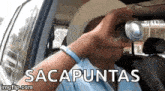 a man is sitting in a car holding a can of soda in front of his eyes .