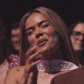 a woman with a tattoo on her shoulder is smiling with her hands crossed