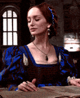 a woman in a blue and brown dress is sitting at a table