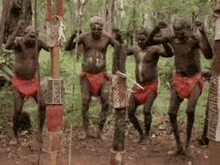 a group of aboriginal men are dancing in a forest .