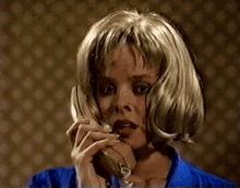 a woman in a blue shirt is talking on a phone