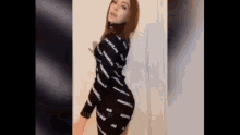 a woman is standing in front of a white curtain wearing a black bodysuit .