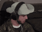 a man wearing headphones and a hat is sitting in front of a chair that says nob