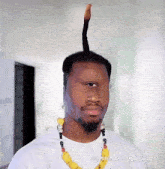 a man wearing a white shirt and a yellow necklace has a very long haircut