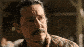 a man with a beard and a plaid shirt is looking at the camera