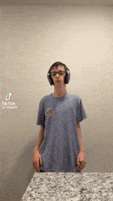 a boy wearing headphones and a blue shirt with a hamburger on it is standing on a counter