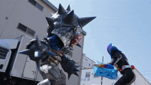 a monster with spikes is being attacked by a man in a blue mask