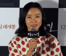 a woman in a polka dot shirt holds a microphone