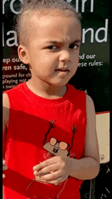 a young boy in a red tank top is standing in front of a sign that says " keep our ren safe "