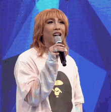 a woman singing into a microphone wearing a white shirt with a picture of a ape on it
