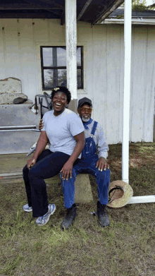 a man in overalls sits on a rock next to a woman
