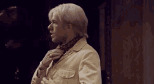 a man with white hair and a scarf around his neck is standing in a room .
