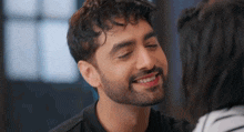a man with a beard is smiling while a woman looks on .