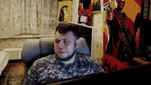 a man with a beard is sitting in a chair in front of a computer screen .
