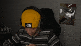 a person wearing a yellow hat that says the north face