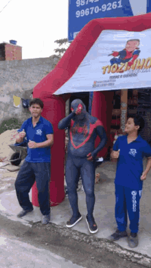 a man in a spiderman costume stands in front of a sign that says tiozinho