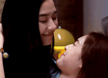 a woman is kissing another woman on the cheek while wearing a blue bracelet