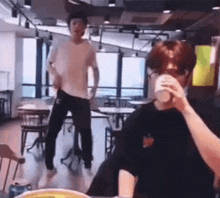 a man is dancing in a restaurant while a woman drinks from a cup .