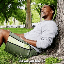 a man is sitting under a tree in a park and asking if he just took it .