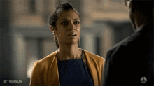 a woman in a blue dress is talking to a man in a black shirt .