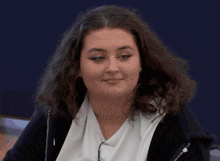 a woman wearing a white shirt and a black jacket is smiling