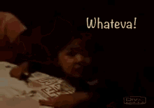 a baby is laying on a table with a person holding it and a sign that says `` whateva ! ''