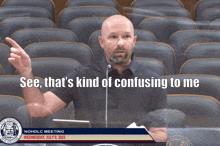 a man stands in front of a microphone with the words see that 's kind of confusing to me above him