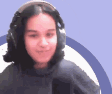 a woman wearing headphones is smiling in front of a purple circle .