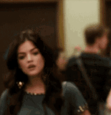 a woman in a blue dress is standing in a room with a blurry background .