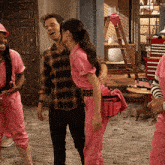 a man and a woman are standing next to each other and the woman is wearing pink overalls