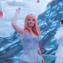a man with a beard and pink hair is dancing in front of a blue background made with reface app