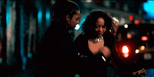 a man with dreadlocks is hugging a woman in a dark room