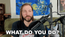 a man with long hair and a beard stands in front of a microphone asking what do you do