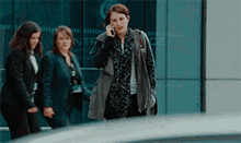 a woman talking on a cell phone in front of a building that has the word entrance on it